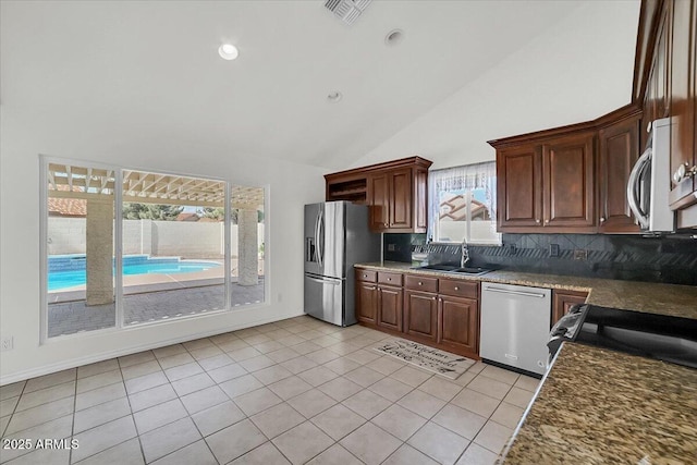 kitchen featuring dark stone countertops, sink, decorative backsplash, and appliances with stainless steel finishes