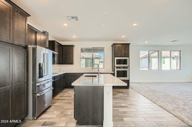 kitchen with stainless steel appliances, a wealth of natural light, a center island with sink, and sink