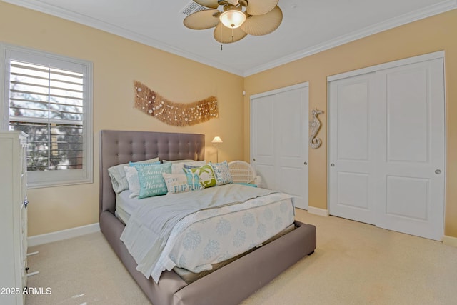 carpeted bedroom featuring ceiling fan, ornamental molding, and multiple closets