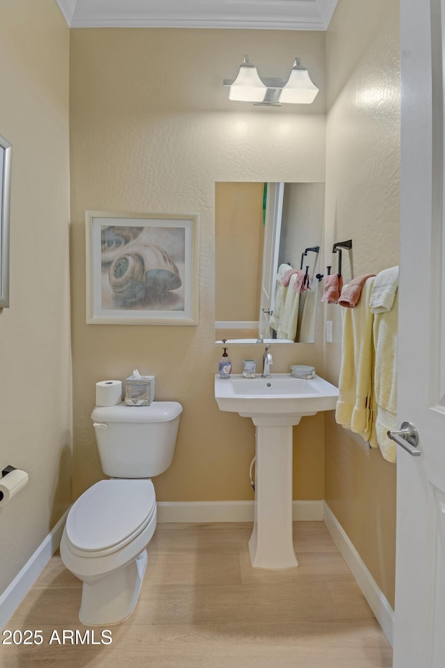 bathroom with hardwood / wood-style flooring, toilet, and crown molding