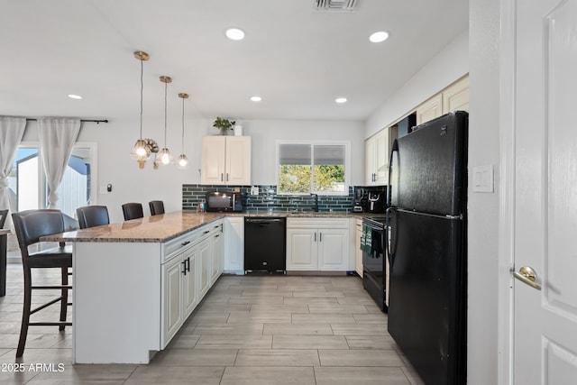 kitchen featuring a kitchen bar, tasteful backsplash, decorative light fixtures, kitchen peninsula, and black appliances