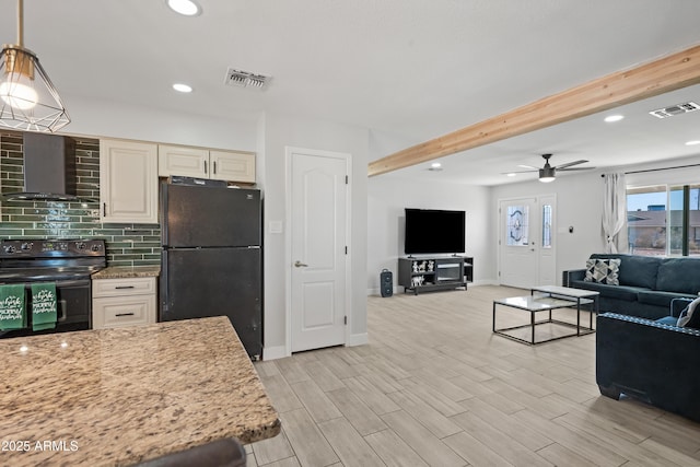 kitchen with hanging light fixtures, wall chimney exhaust hood, light stone counters, and black appliances