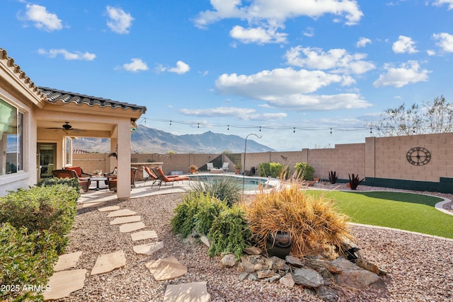 view of yard with a fenced in pool, ceiling fan, a mountain view, and a patio area