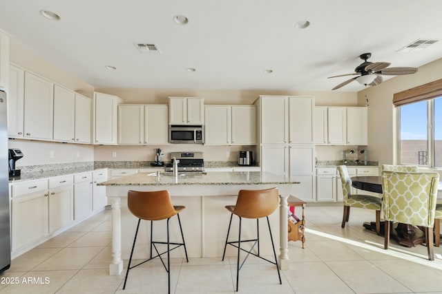 kitchen with a kitchen island with sink, light stone counters, and stainless steel appliances