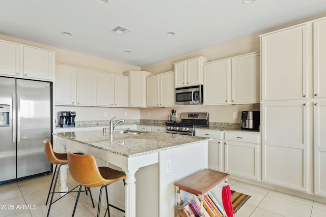 kitchen featuring a breakfast bar, sink, light tile patterned floors, an island with sink, and stainless steel appliances