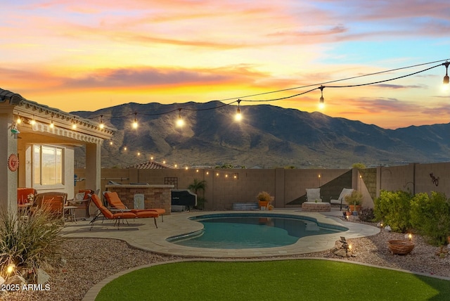 pool at dusk featuring a mountain view and a patio