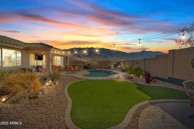 yard at dusk featuring a fenced in pool, a patio, and a mountain view