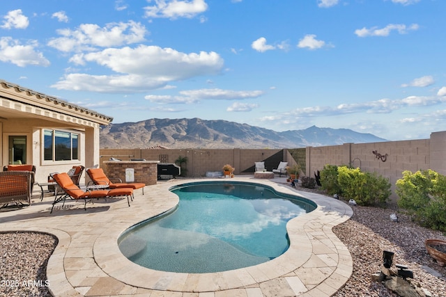 view of swimming pool featuring a mountain view, a patio, and exterior kitchen