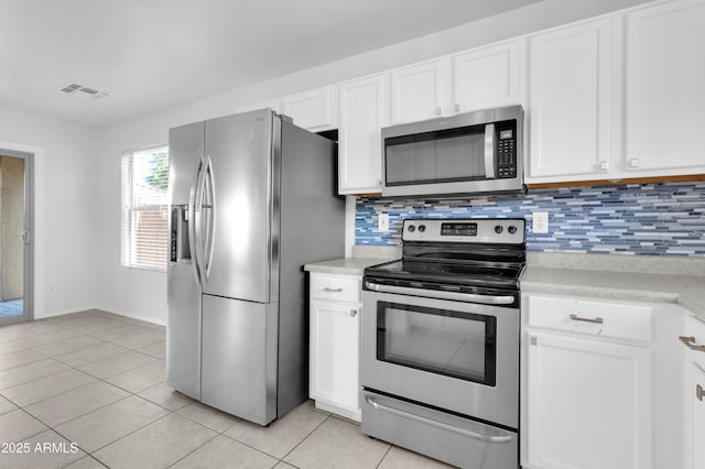 kitchen featuring backsplash, white cabinets, light tile patterned flooring, and appliances with stainless steel finishes