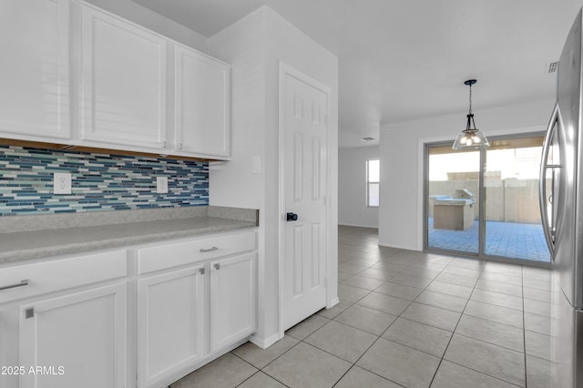 kitchen with white cabinets, pendant lighting, light tile patterned floors, and stainless steel refrigerator