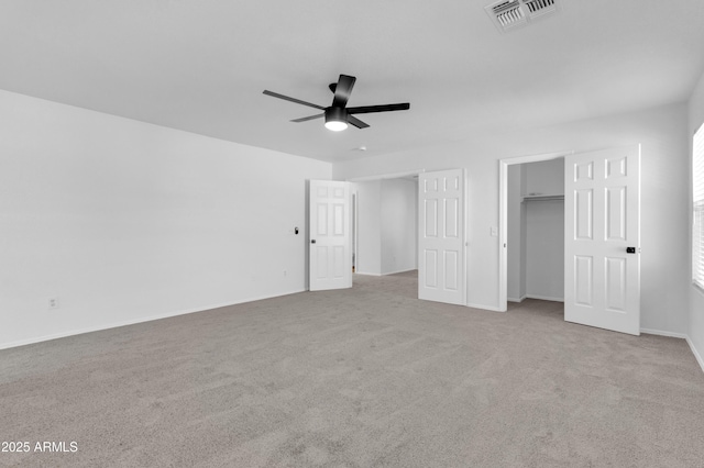 unfurnished bedroom with light colored carpet, a spacious closet, and ceiling fan