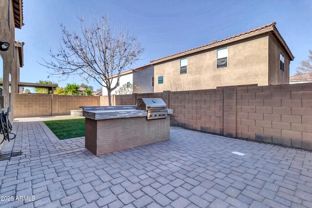 view of patio / terrace featuring exterior kitchen and a grill