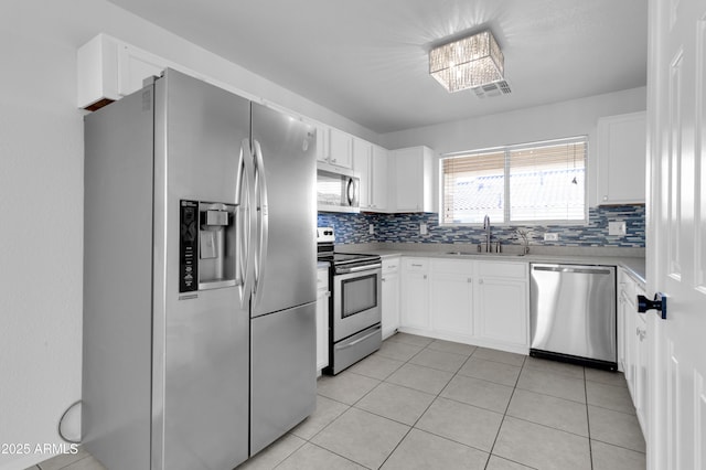 kitchen with white cabinets, sink, light tile patterned floors, a notable chandelier, and stainless steel appliances