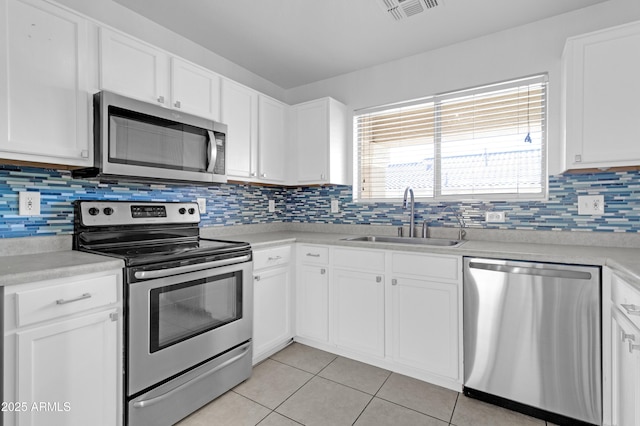 kitchen with white cabinets, sink, light tile patterned floors, tasteful backsplash, and stainless steel appliances