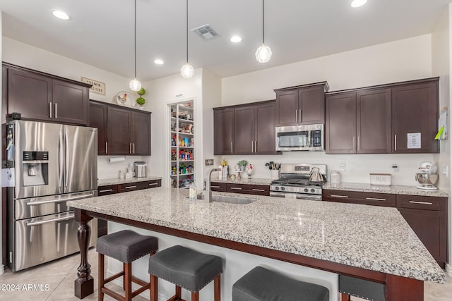 kitchen featuring sink, an island with sink, a kitchen breakfast bar, stainless steel appliances, and decorative light fixtures