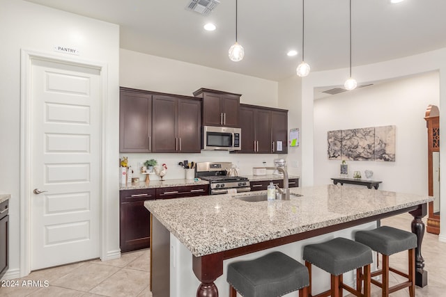 kitchen featuring dark brown cabinetry, a kitchen island with sink, stainless steel appliances, and sink