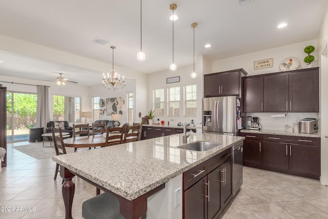 kitchen with an island with sink, sink, decorative light fixtures, stainless steel appliances, and ceiling fan with notable chandelier