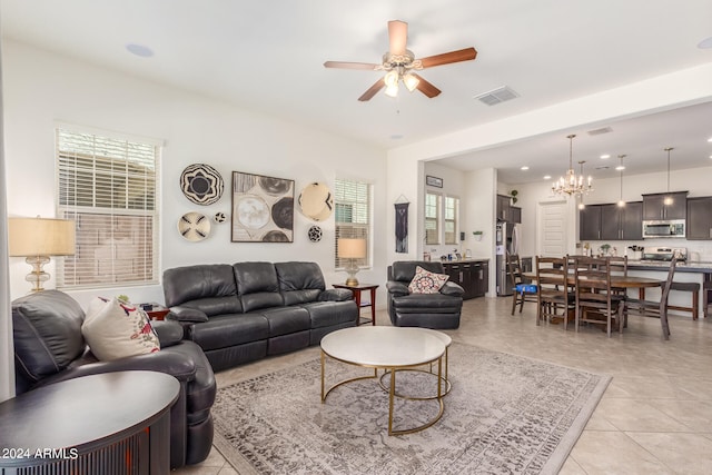 tiled living room featuring ceiling fan with notable chandelier