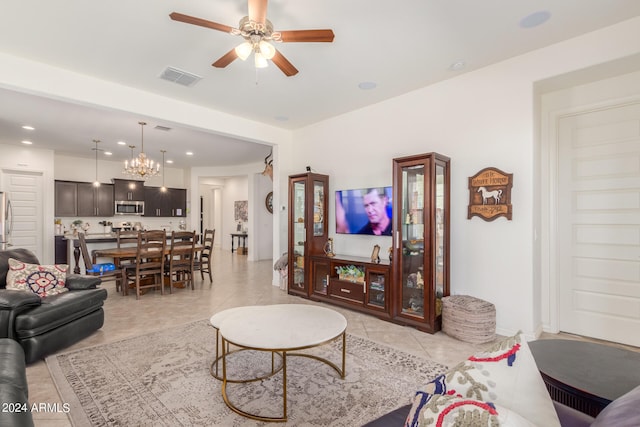 tiled living room with ceiling fan with notable chandelier