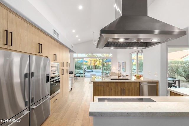 kitchen with appliances with stainless steel finishes, light brown cabinets, a sink, island range hood, and modern cabinets