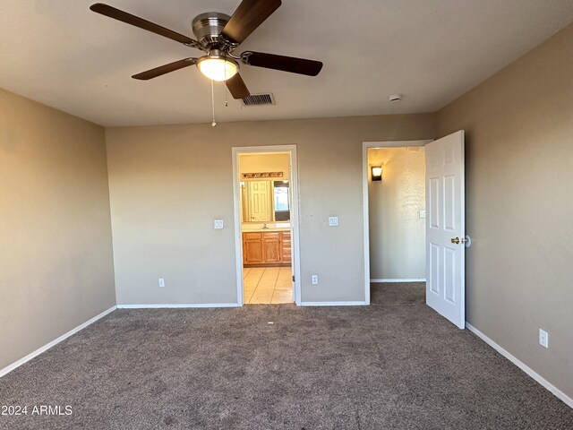 unfurnished bedroom with light colored carpet, ceiling fan, and connected bathroom