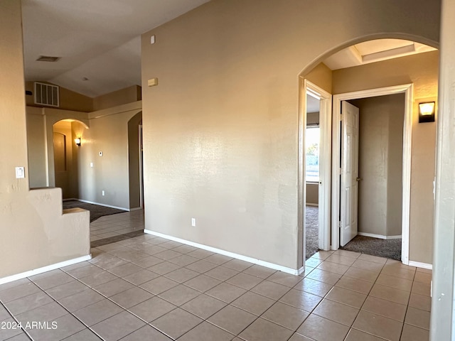 empty room featuring vaulted ceiling and light tile patterned floors