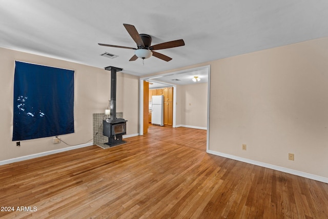 unfurnished living room featuring hardwood / wood-style floors, a wood stove, and ceiling fan