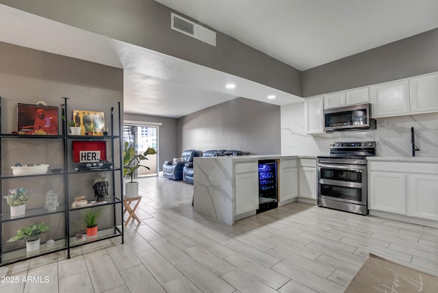 kitchen with wine cooler, sink, white cabinets, and appliances with stainless steel finishes