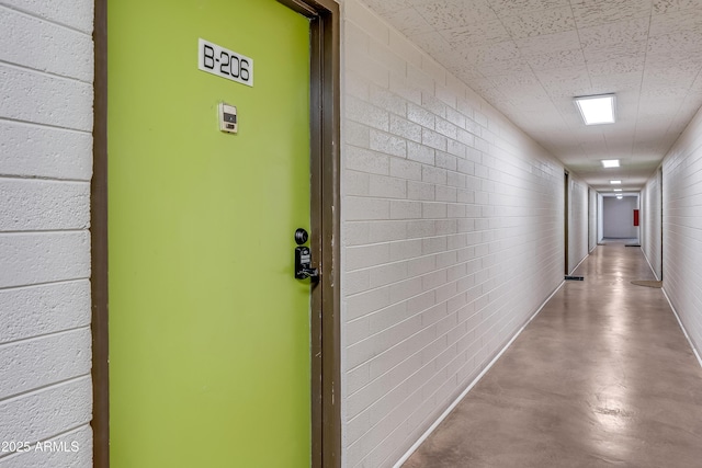 corridor featuring concrete flooring and brick wall