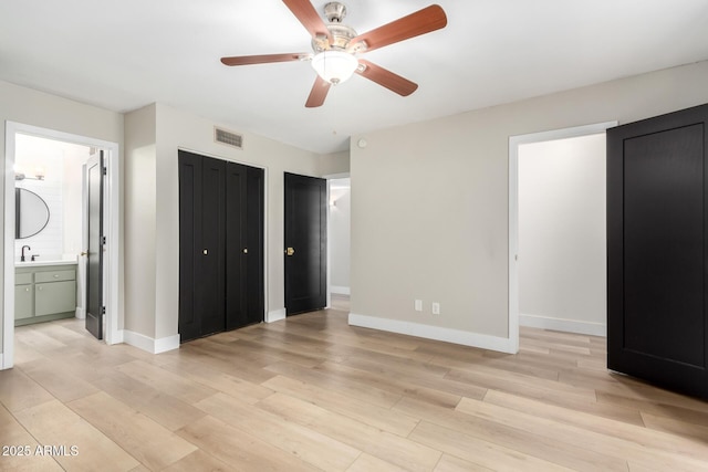 unfurnished bedroom featuring sink, light wood-type flooring, ceiling fan, and ensuite bathroom