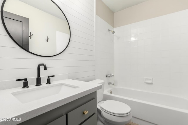 full bathroom featuring vanity, tiled shower / bath, wooden walls, and toilet