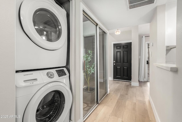 laundry area with stacked washer / drying machine and light wood-type flooring