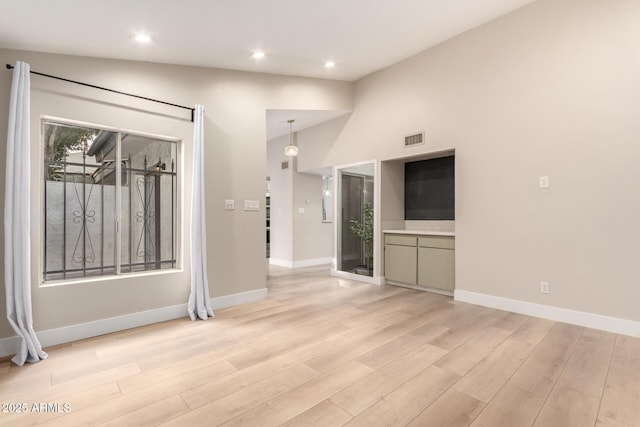 unfurnished living room with vaulted ceiling and light wood-type flooring