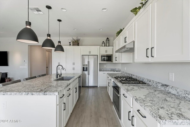 kitchen with white cabinets, a center island with sink, appliances with stainless steel finishes, and sink