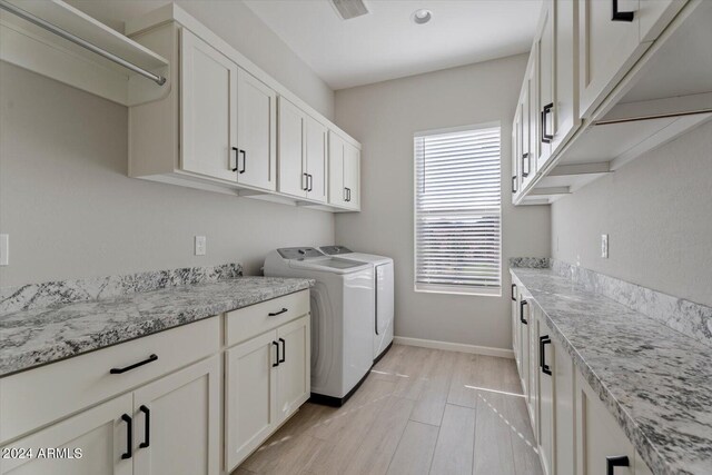 clothes washing area with cabinets, light hardwood / wood-style flooring, and independent washer and dryer