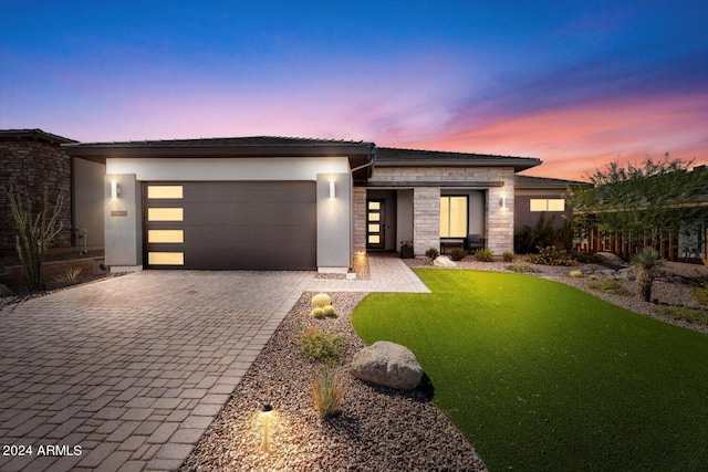 prairie-style home featuring a garage and a lawn