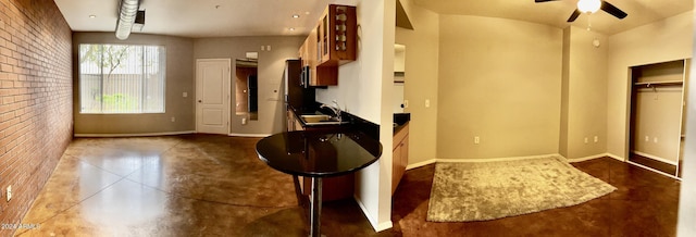 kitchen with sink, a breakfast bar, ceiling fan, and brick wall