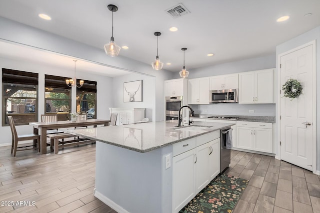 kitchen with hanging light fixtures, white cabinetry, sink, and appliances with stainless steel finishes