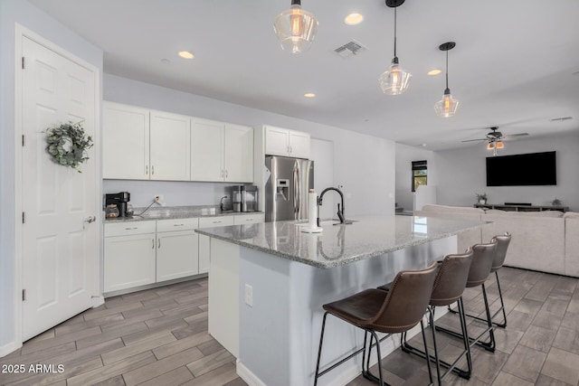 kitchen with white cabinetry, stainless steel fridge, ceiling fan, and hanging light fixtures