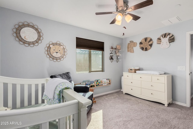 carpeted bedroom featuring ceiling fan and a nursery area