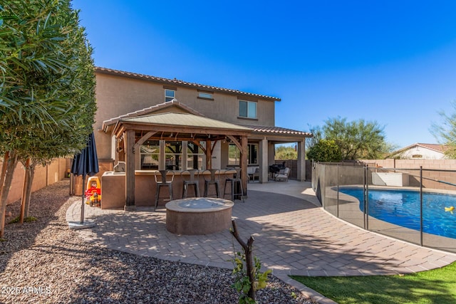 back of house with a gazebo, a patio area, a bar, and a fenced in pool