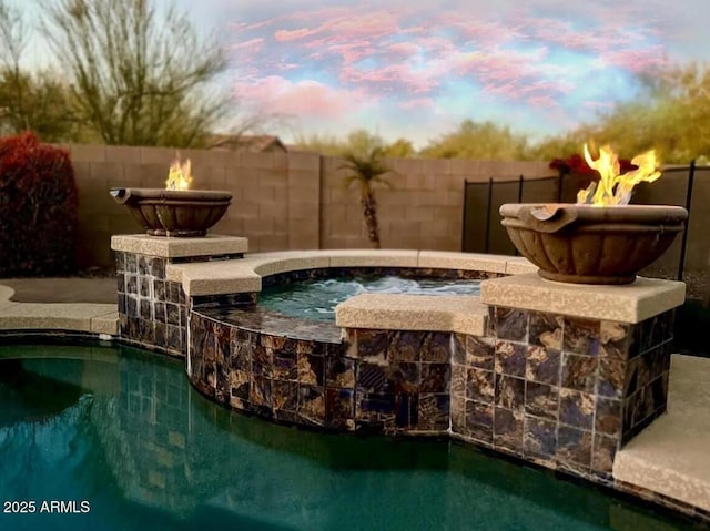 pool at dusk featuring a hot tub and an outdoor fire pit