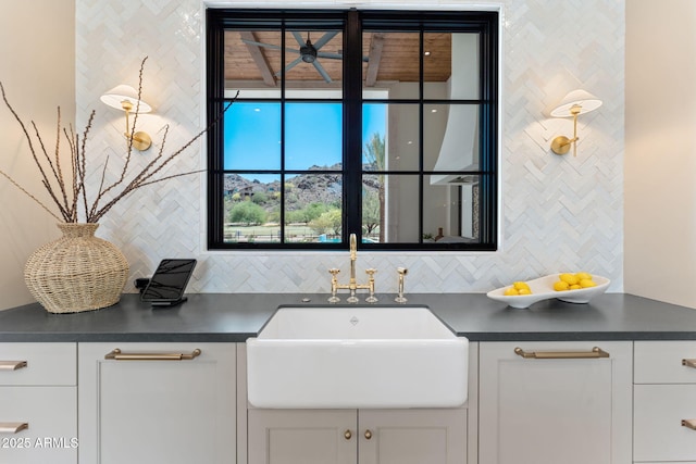 kitchen featuring white cabinetry, dark countertops, decorative backsplash, and a sink