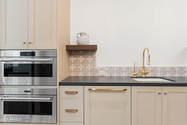 kitchen featuring a sink, dark countertops, tasteful backsplash, and double oven