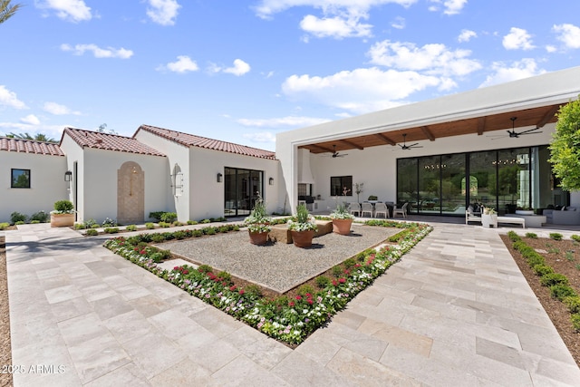 rear view of house with a tile roof, stucco siding, outdoor lounge area, a patio area, and a ceiling fan