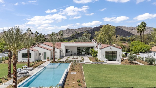 back of house with a patio, an outdoor pool, stucco siding, a mountain view, and a yard