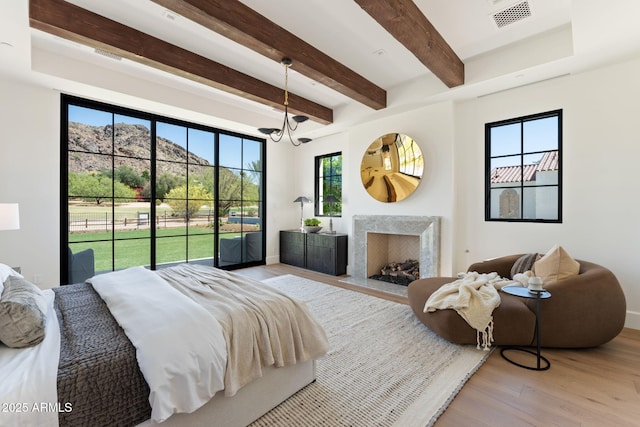 bedroom featuring visible vents, wood finished floors, access to exterior, beamed ceiling, and a high end fireplace