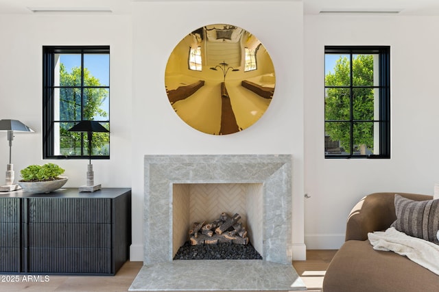 living room featuring baseboards, a high end fireplace, wood finished floors, and a wealth of natural light