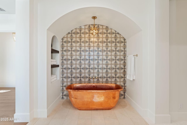 details featuring a freestanding tub, visible vents, built in shelves, and baseboards