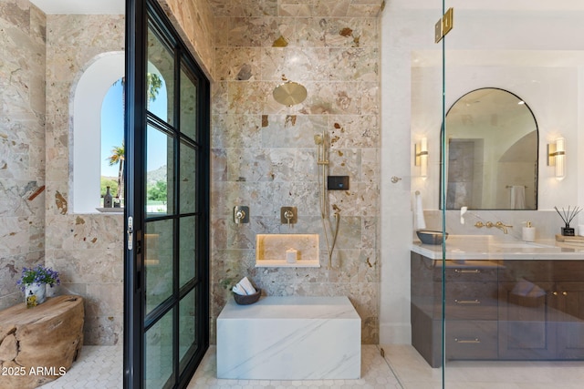 full bathroom featuring vanity, a bath, and tile walls